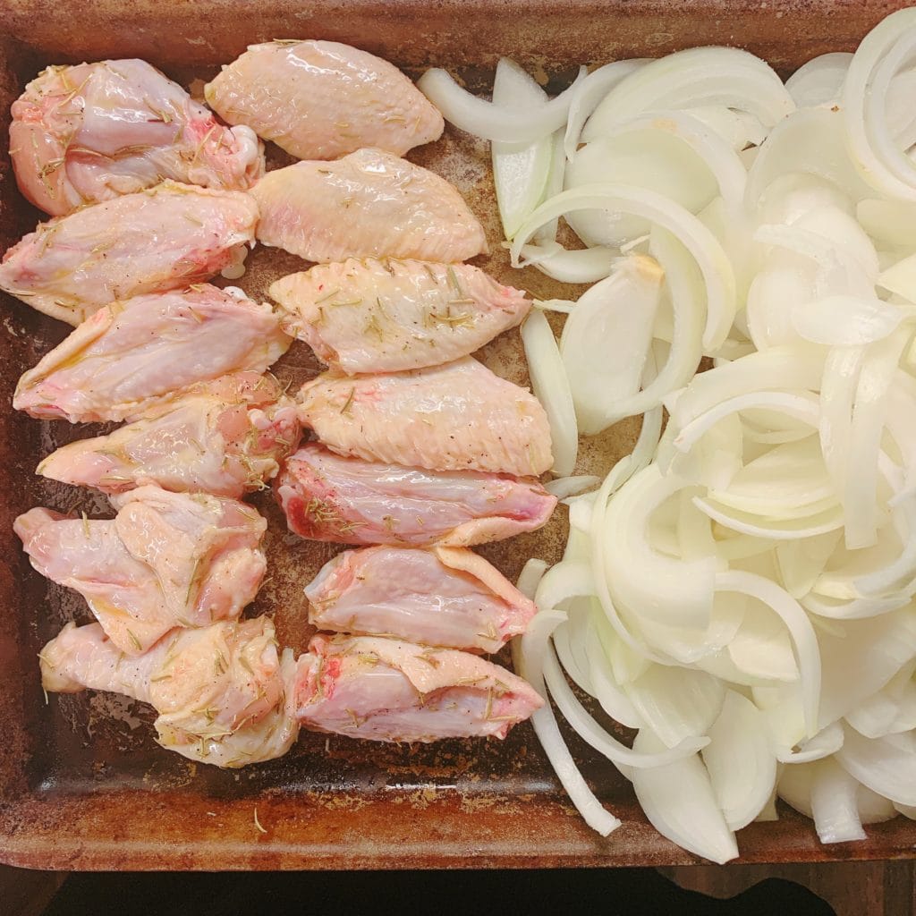 seasoned wings and chopped onions on a pan