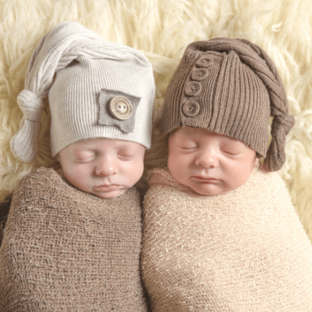 breastfeeding twins articles 2 newborn babies laying side by side bundled and wearing hats