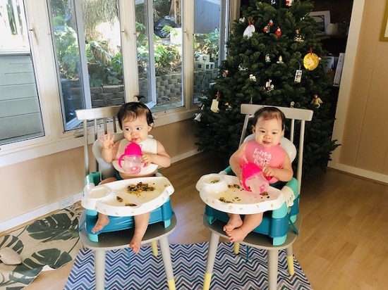 Christmas when you're broke. Twins sitting in high chairs eating in front of a Christmas tree