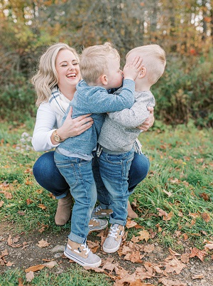 post twins body a woman smiling as her twins toddler boys hug and kiss each other outside