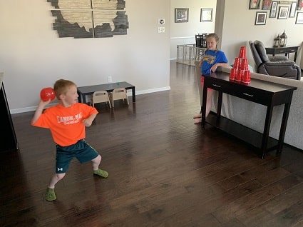 indoor physical activities a boy throwing a balloon at a stack of cups