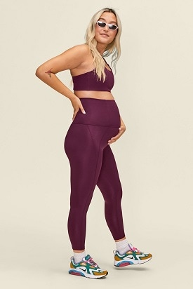 maternity leggings a pregnant woman wearing sunglasses, a purple sports bra and matching leggings