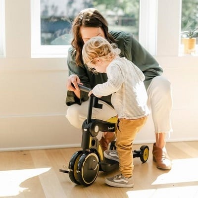 toddler scooter a woman holding a scooter to help a toddler step on in a house