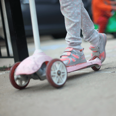 toddler scooter small feet on a 3-wheeled scooter on pavement