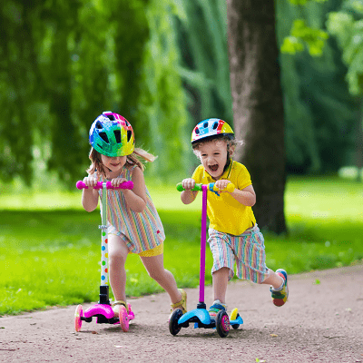 toddler scooter a little boy and a little girl riding on scooters in a park