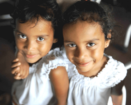 twins are not genetic clones young girl twins smiling at the camera, wearing matching shirts