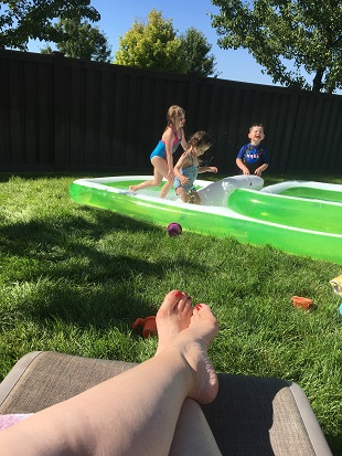 different parenting 3 young kids playing with water in a backyard