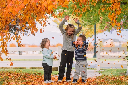 different parenting 3 young kids playing in falling leaves