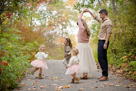 A family of five playing outside on a sidewalk 