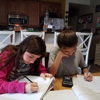 twin girls doing homework at a table together