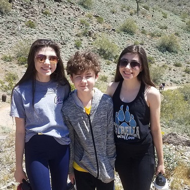 teen twins and a boy standing outside on a desert trail