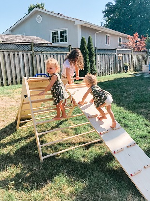 three young children playing on an outdoor jungle gym