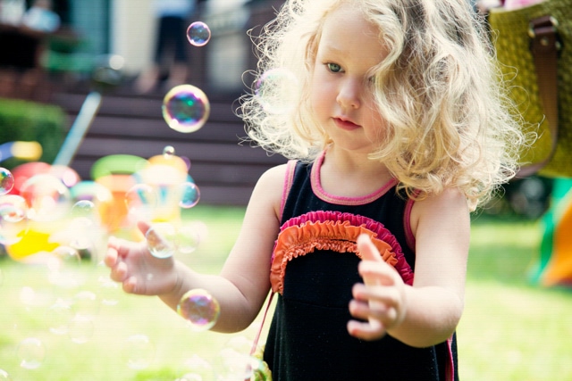 little girl playing with bubbles in the backyard
