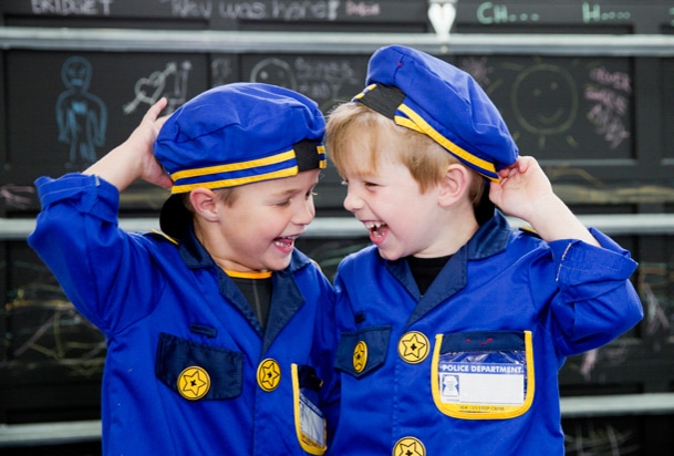 twin toddler boys in play police uniforms laughing