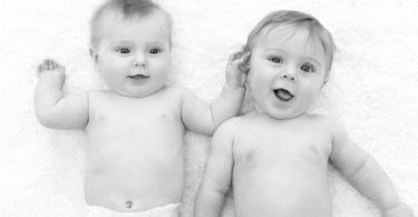twin baby boys in diapers laying on the floor