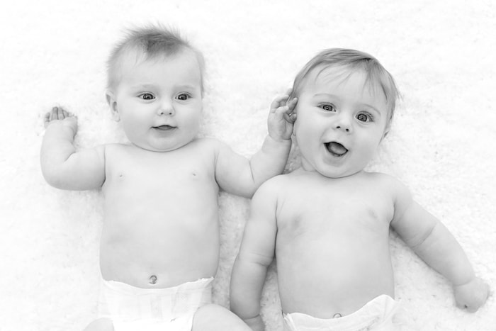 twin baby boys in diapers laying on the floor