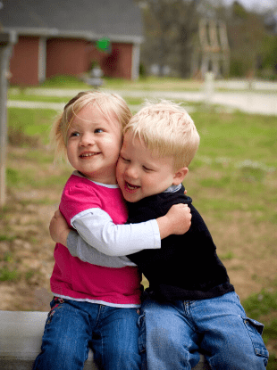 boy girl twins hugging each other sitting outside