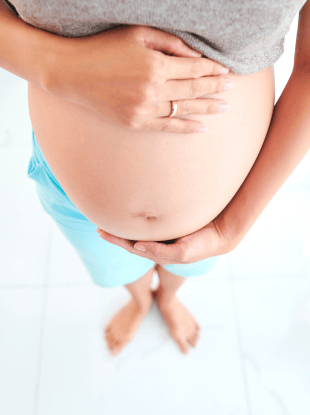 a woman's hands holding her pregnant belly