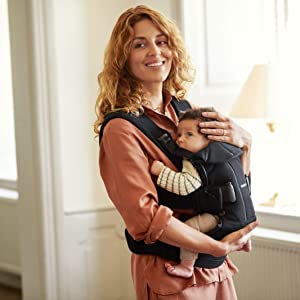 a woman holding an infant in a front carrier