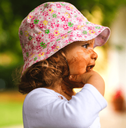 toddler in a pink hat with messy face and hand