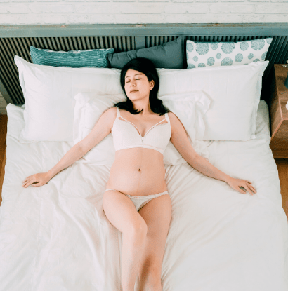 woman sleeping in bed in pregnancy lingerie