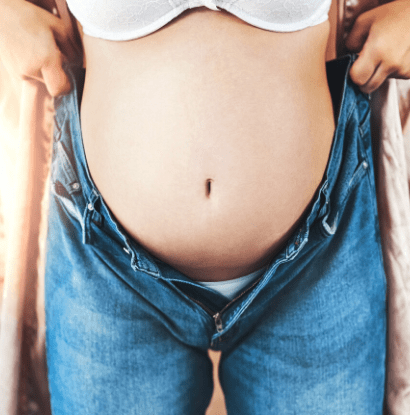pregnant woman holding jeans up
