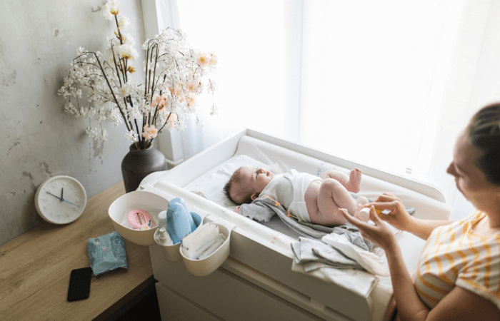 baby laying on a Diaper Changing Station with mom changing a diaper