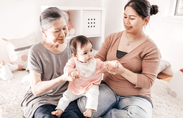 grandma mom and baby sitting on the bed