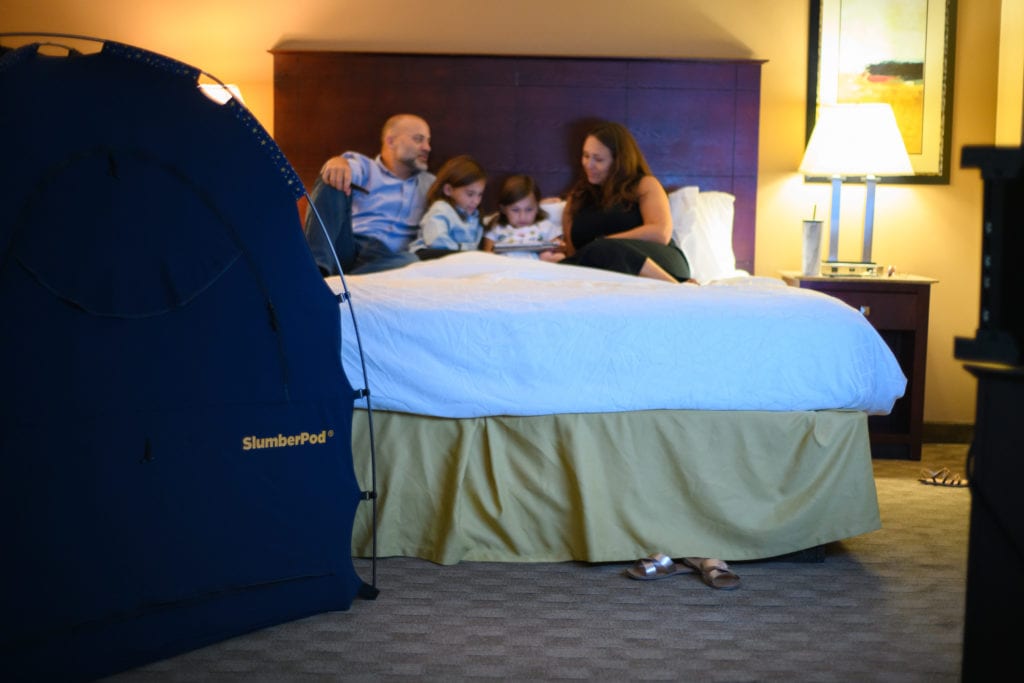 family in a hotel bed with a slumberpod on the side