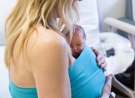 a woman using a neonatal wrap to hold a newborn close