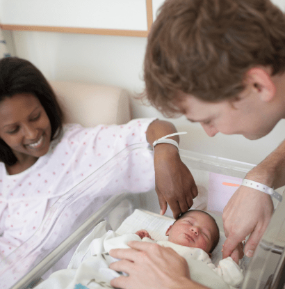 a couple looking at a baby in a nursery bassinet