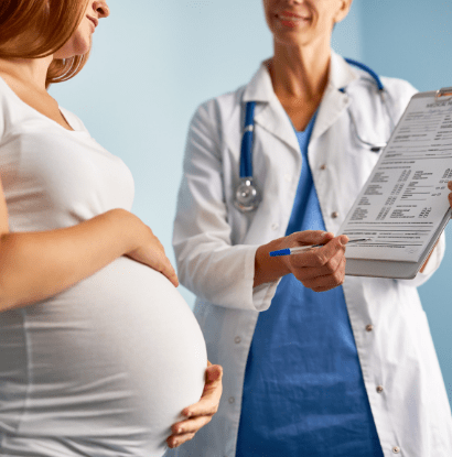 a pregnant woman listening to a doctor as she points at a chart