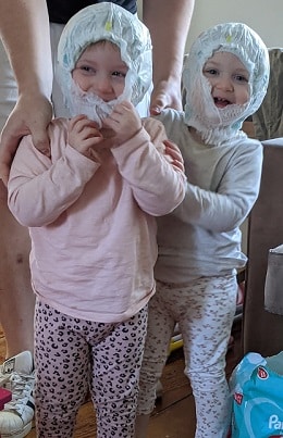 twin toddler laughing with diapers on their heads