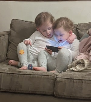 twin girls looking at a phone together on a couch