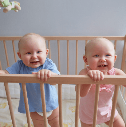 boy girl twins standing in a crib