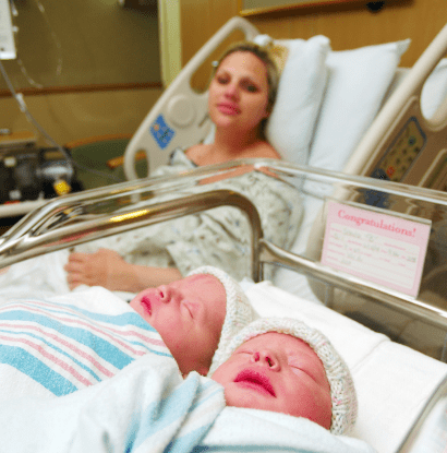 twins in hospital crib and woman in hospital bed