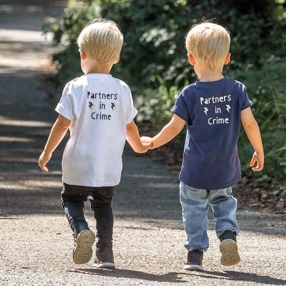 twin boys walking hand in hand, being confident and exploring a bit on their own