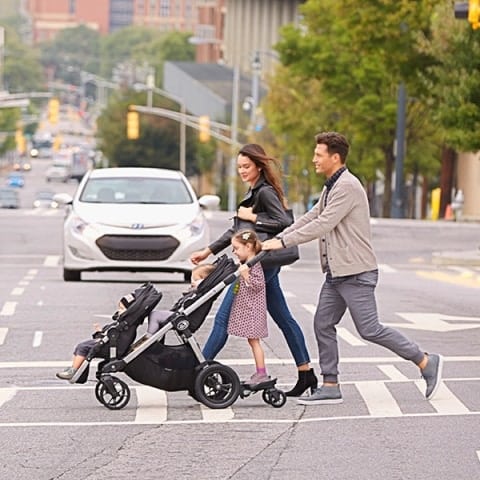 a couple with 3 children crossing the street with the Baby Jogger City Select Double Stroller and glider board attachment