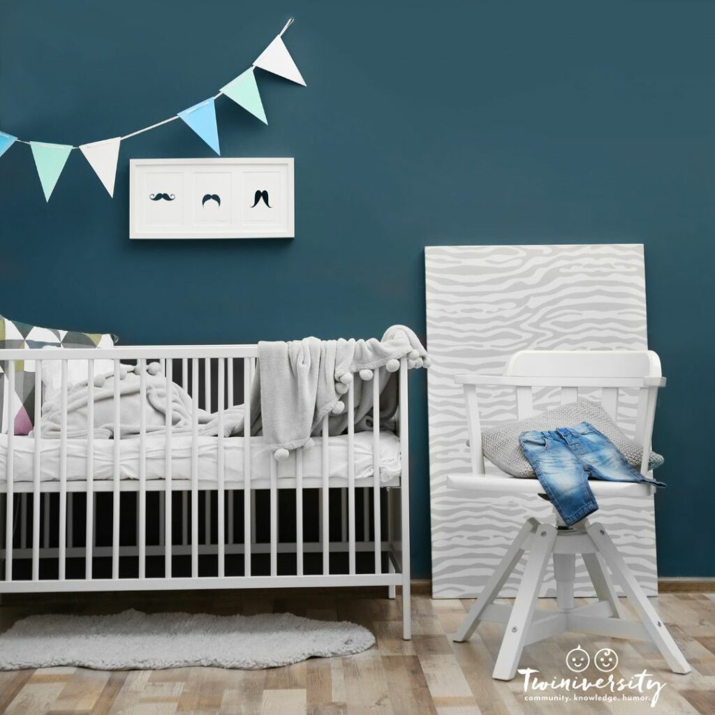 A dark teal wall behind a white wood crib can be great for a boy's nursery theme