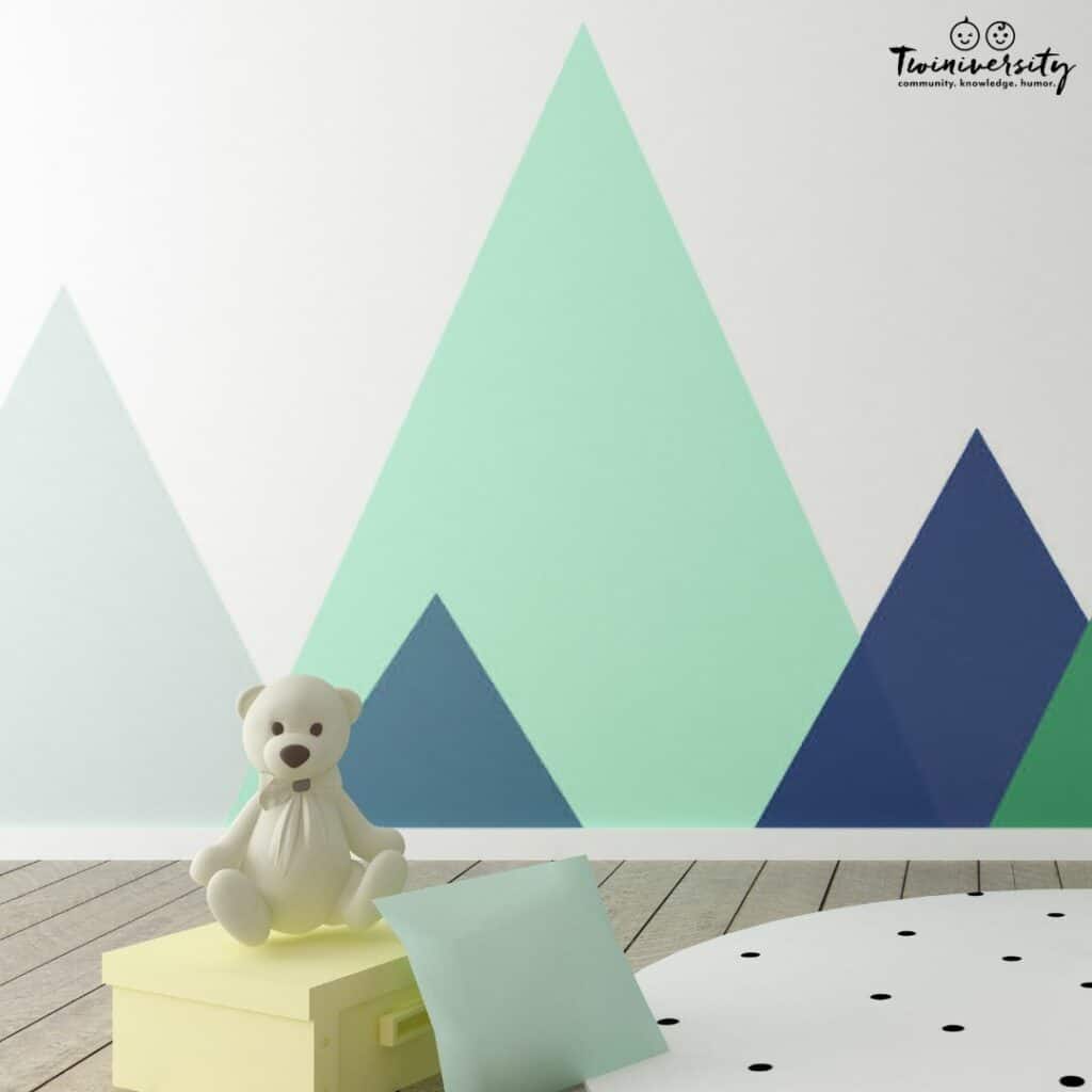 Baby boy nursery with large blue and green triangles on the wall to look like mountains. Perfect boy nursery idea.