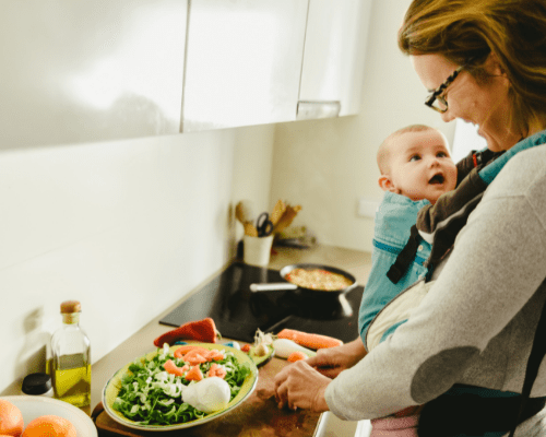 mom preparing dinner with an infant in a front carrier