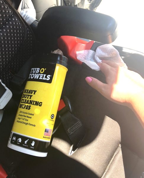 a box of tub o towels and a woman's hand cleaning the cupholder of a car seat