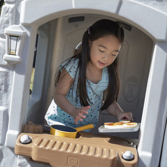 little girl playing in the play kitchen of a playhouse