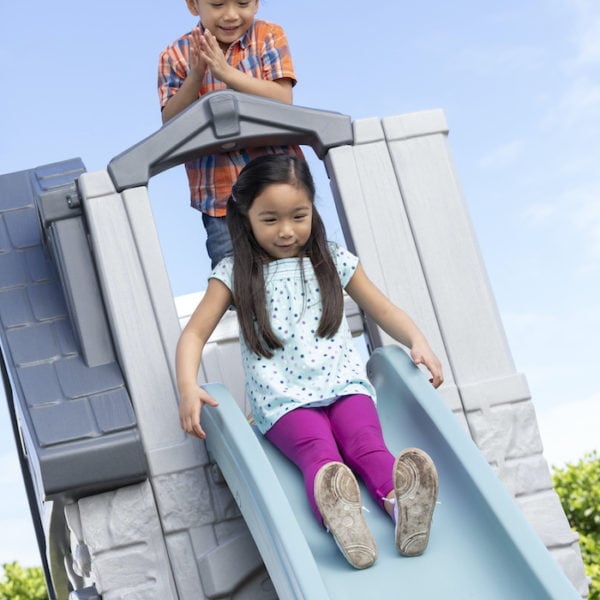 girl sliding down a slide on a playhouse Step2