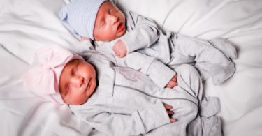 boy girl twins laying on a hospital bed with coming home outfits on