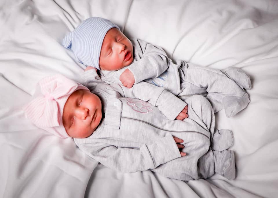 boy girl twins laying on a hospital bed with coming home outfits on