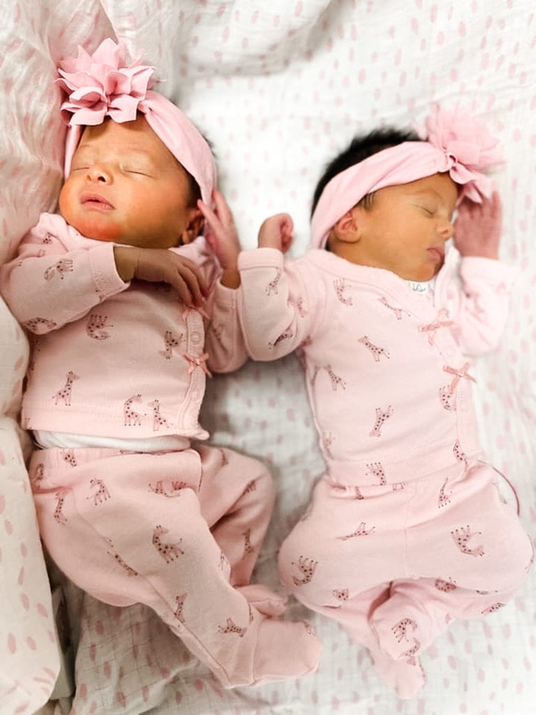baby girl twins laying on a bed sleeping