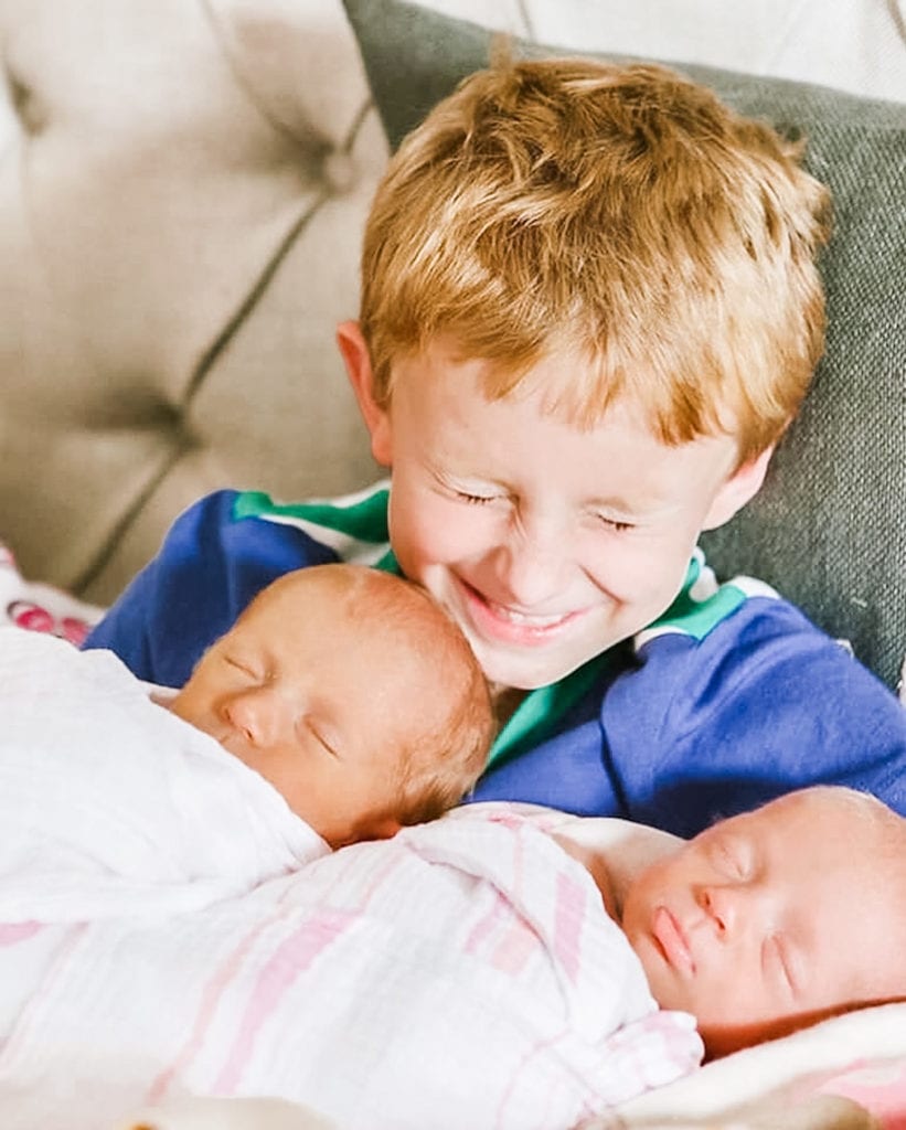 big brother holding newborn twin baby girls