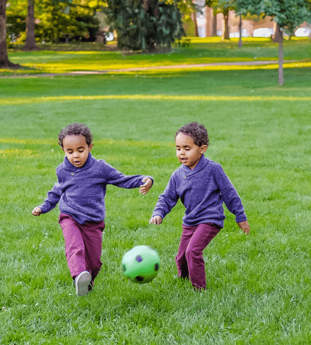 twin boys chasing a soccer ball