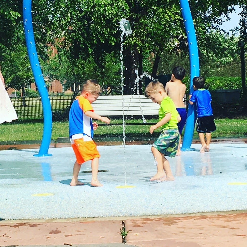 twin boys playing at a splash pad